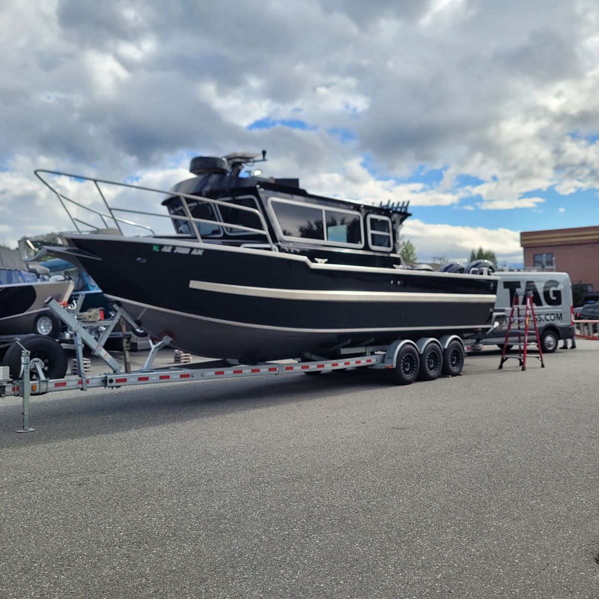Boat on a trailer next to the Todd's Auto Glass van in summer